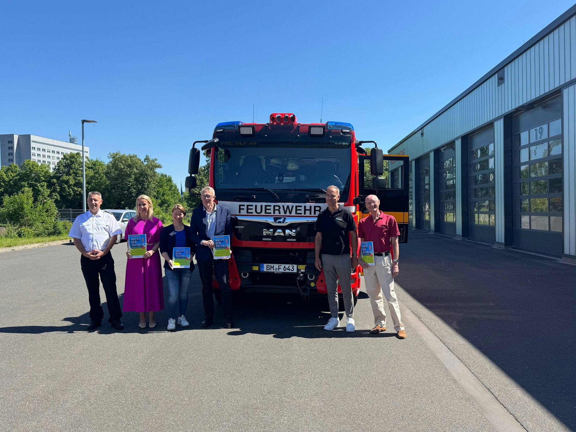 Das Foto zeigt eine Gruppe von Menschen vor einem Feuerwehrwagen an der Feuerwache in Frechen.