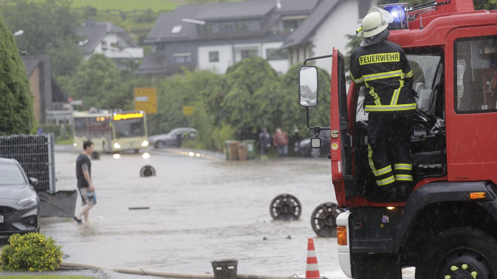 Zu sehen ist eine überflutete Straße, davor ein Fahrzeug der Feuerwehr.