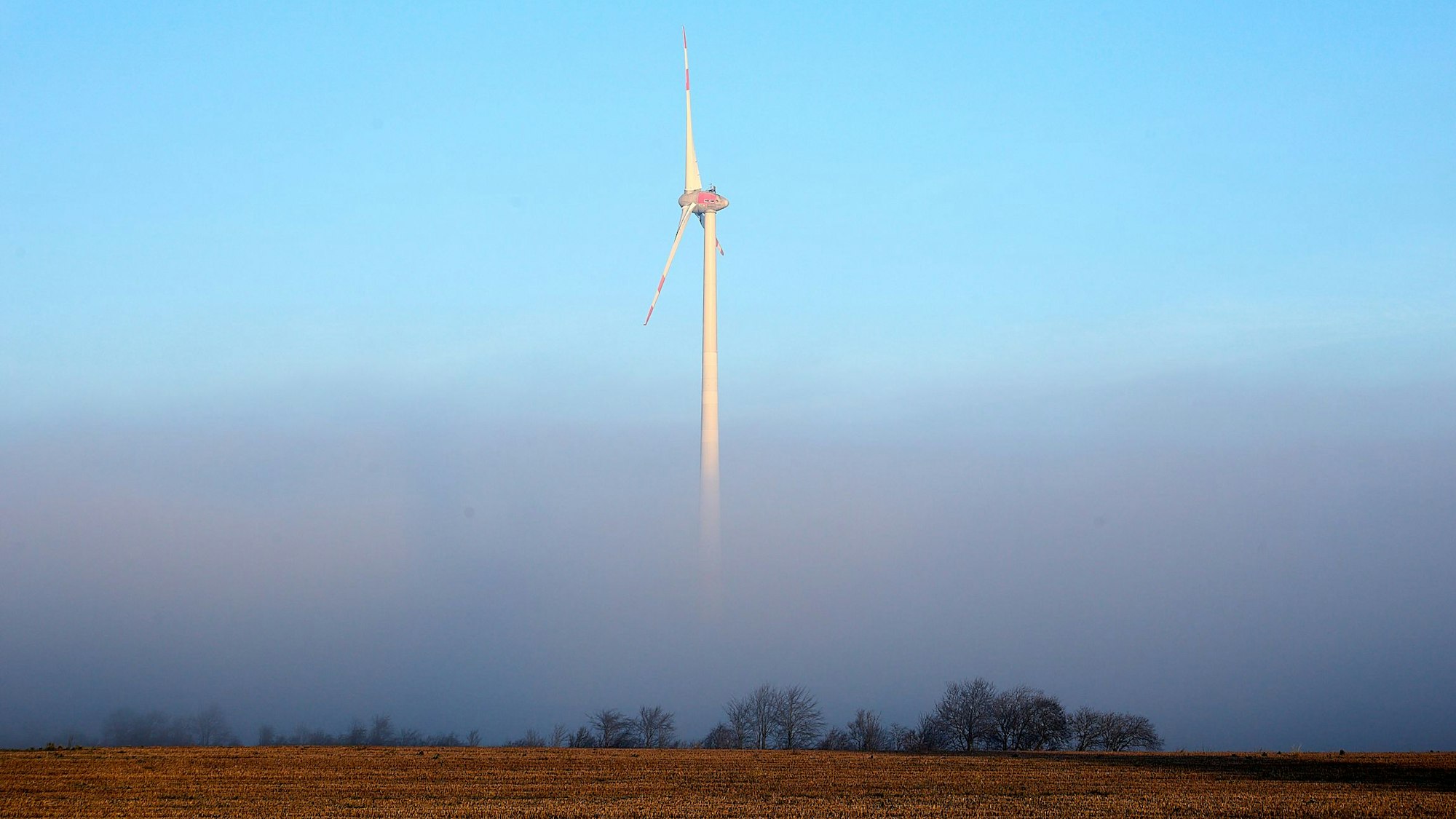 Ein Windrad steht im Nebel.