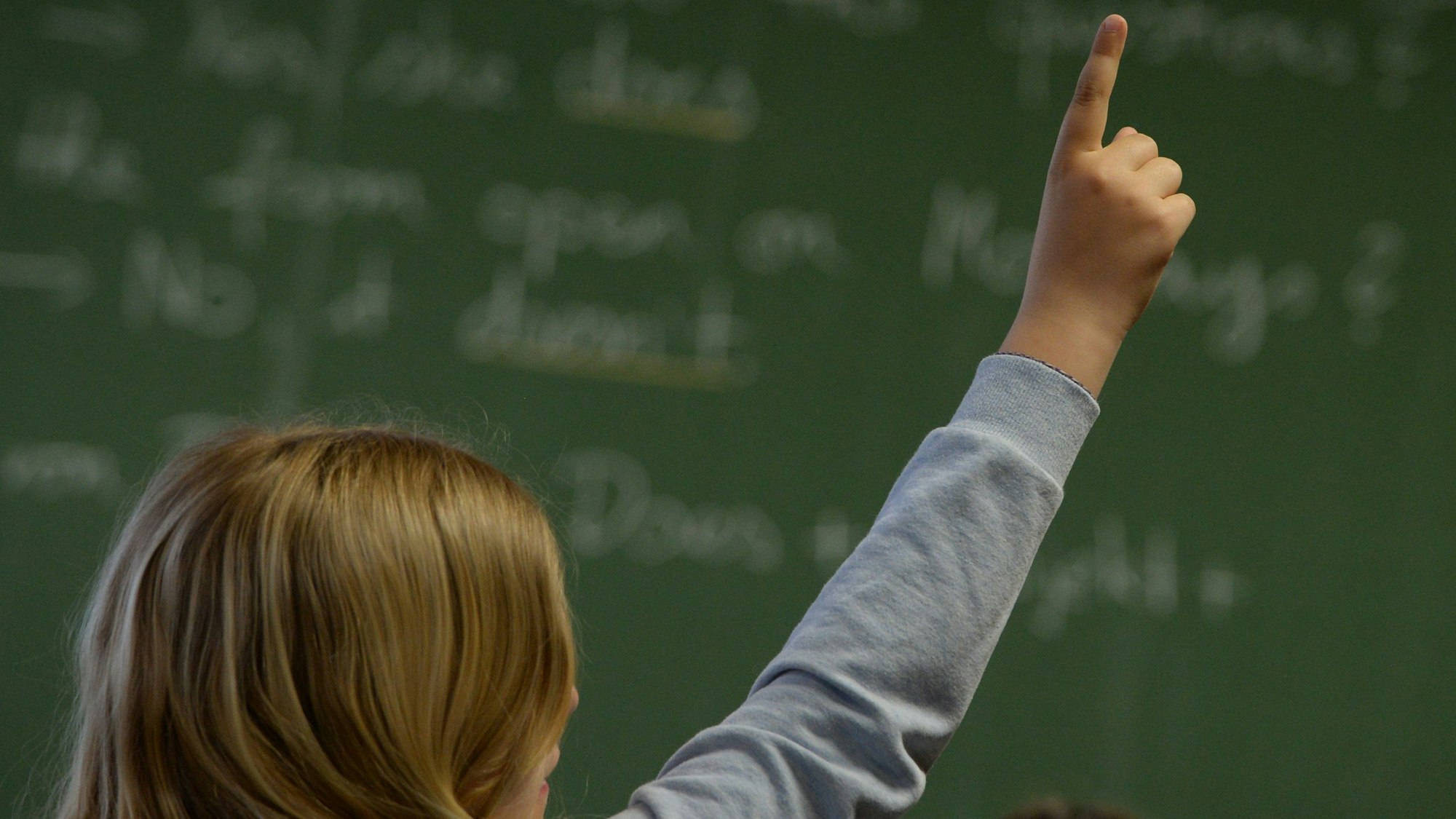 Eine Schülerin meldet sich in einem Klassenzimmer in einem Gymnasium während des Englischunterrichts.