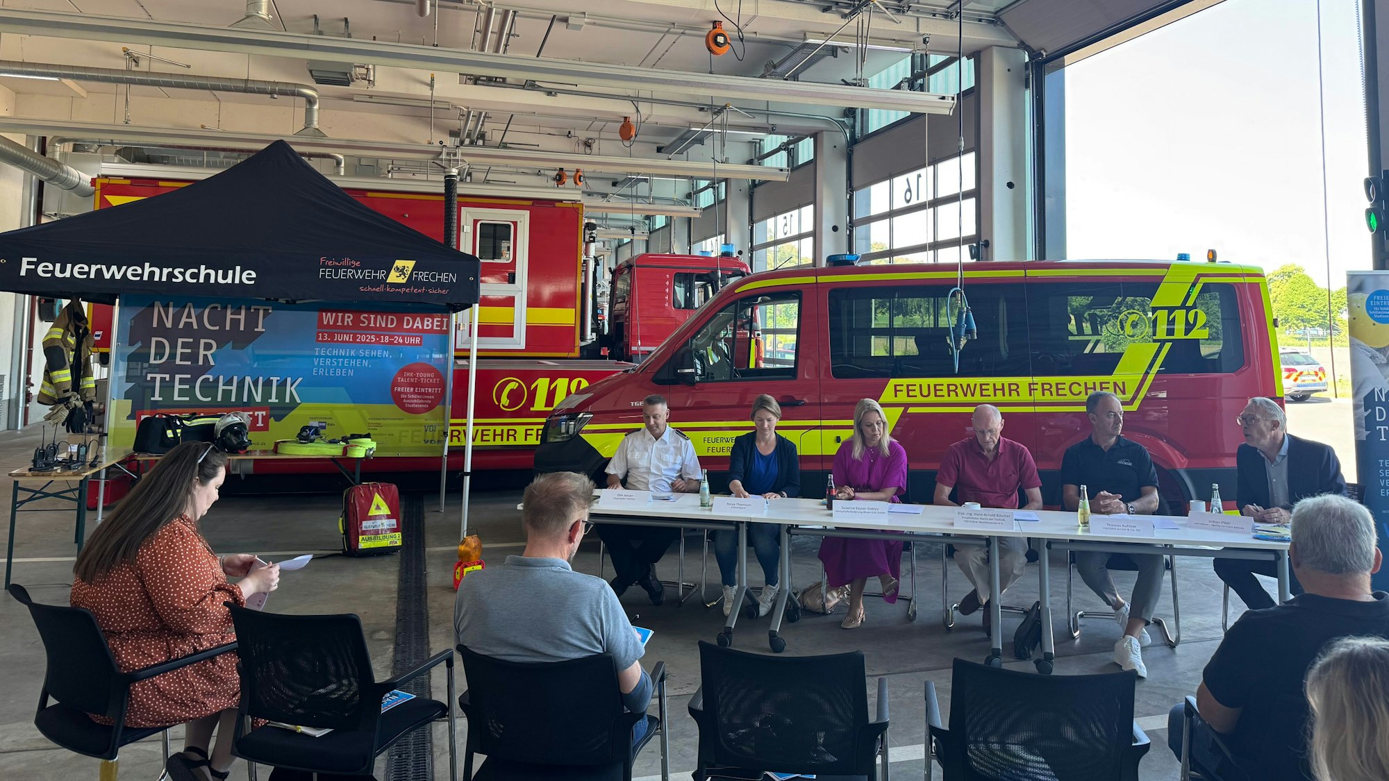 Das Foto zeigt das Podium und Besucher in einer Fahrzeughalle der Feuerwache in Frechen.