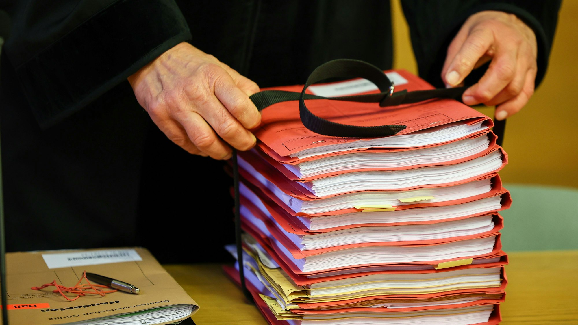 Der Staatsanwalt legt einen Stapel Akten vor Prozessbeginnauf seinen Tisch im Landgericht