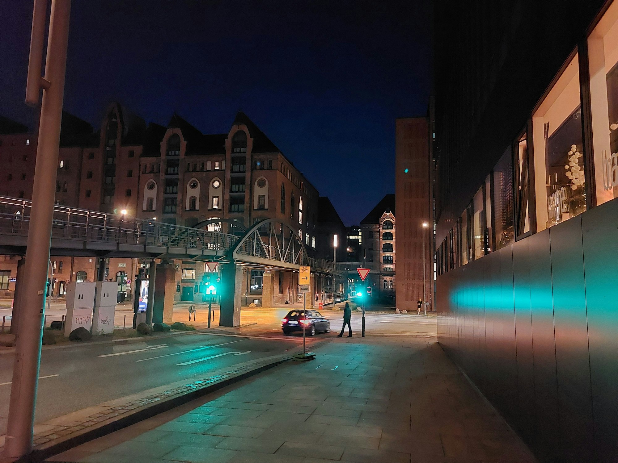 Nächtliche Aufnahme an einer Straßenkreuzung in der Hamburger Speicherstadt. Die Ampel leuchtet grün.