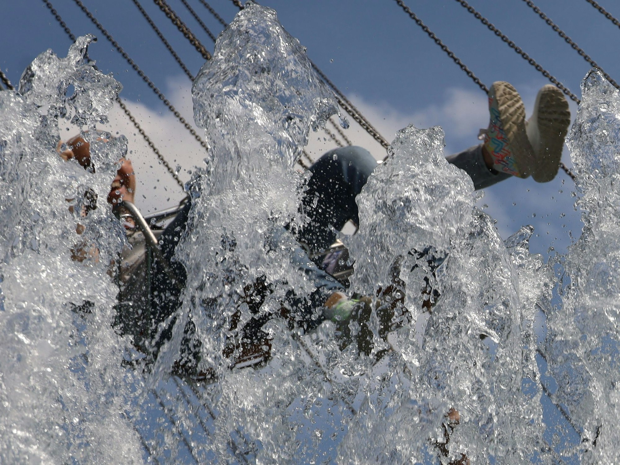 Eine Person wird auf einem Kettenkarussell von Wasser nass gespritzt.