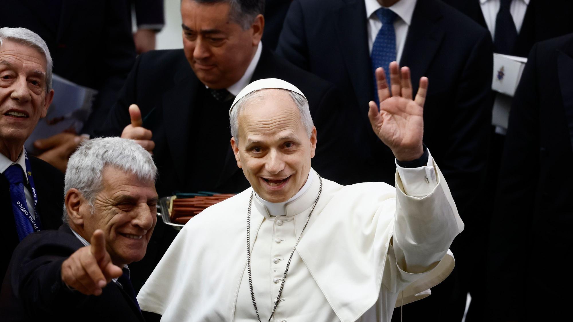 12.05.2025, Vatikan, Vatikanstadt: Papst Leo XIV. winkt während einer Audienz in der Halle Paul VI. im Vatikan am Montag, 12. Mai 2025, Fotografen zu, die über das Konklave, in dem er gewählt wurde, berichtet haben.