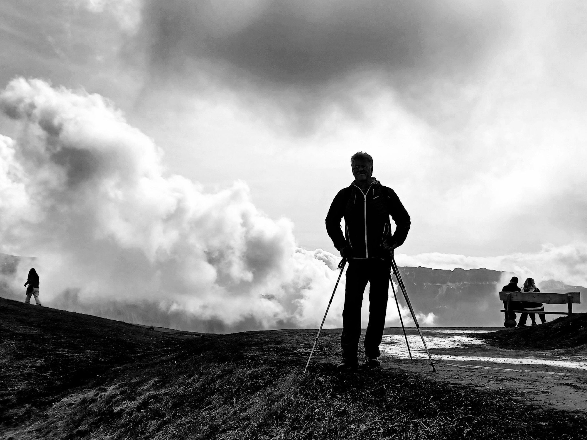 Ein schwarz-weißes Foto von einem Wanderer in den bewölkten Bergen.