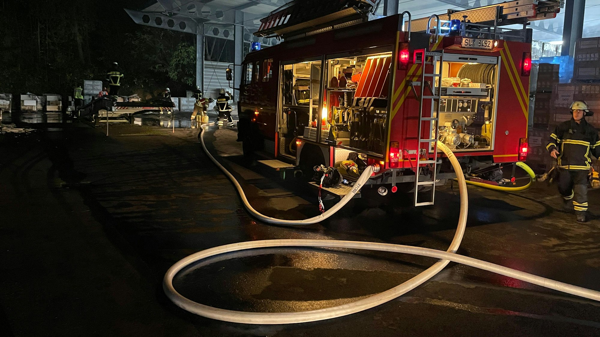 Ein Löschfahrzeug steht vor der offenen Lagerhalle.