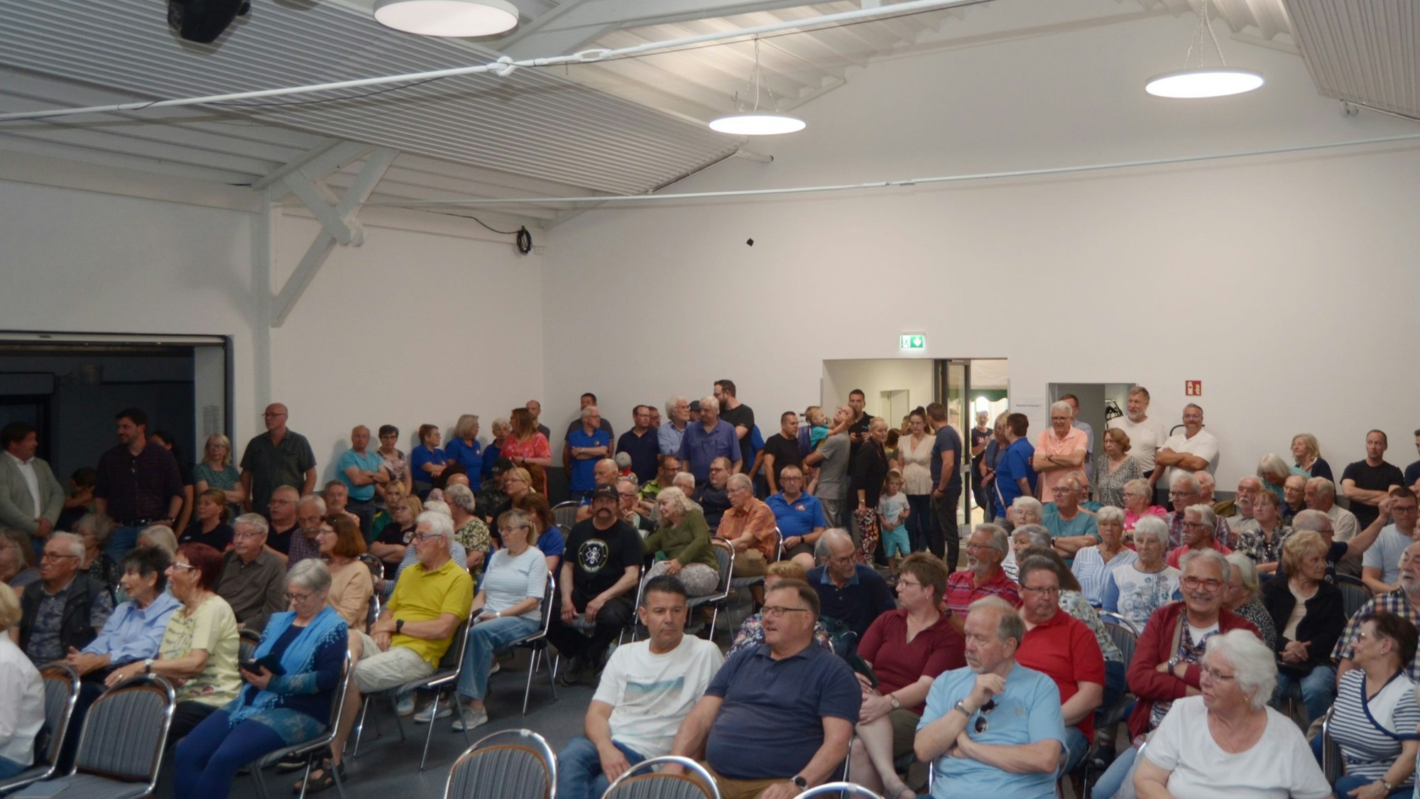 Das Bild zeigt den Saal, der fast voll besetzt ist.