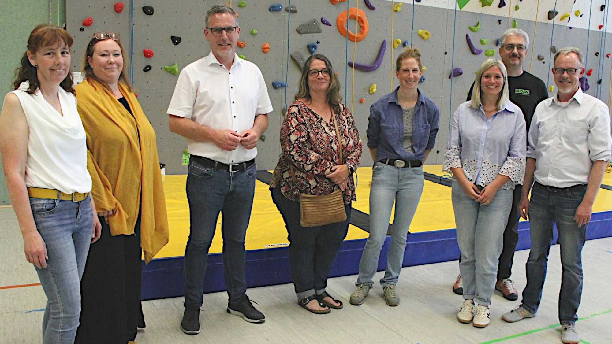 Die Beteiligten haben sich zum Foto vor die Kletterwand gestellt.