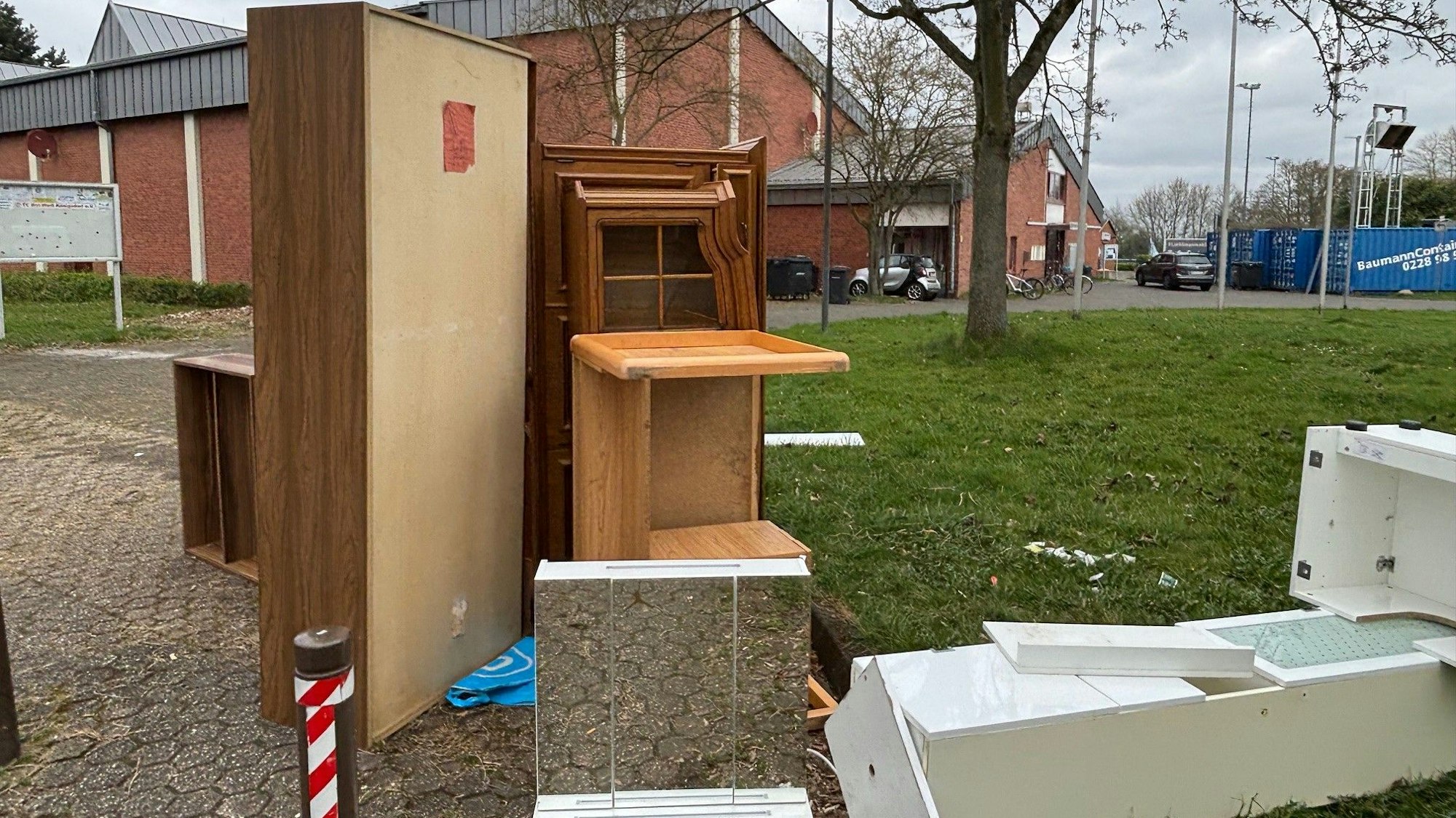 Auf dem Bild ist die Sporthalle zu sehen, vor der ausgeräumter Sperrmüll liegt.