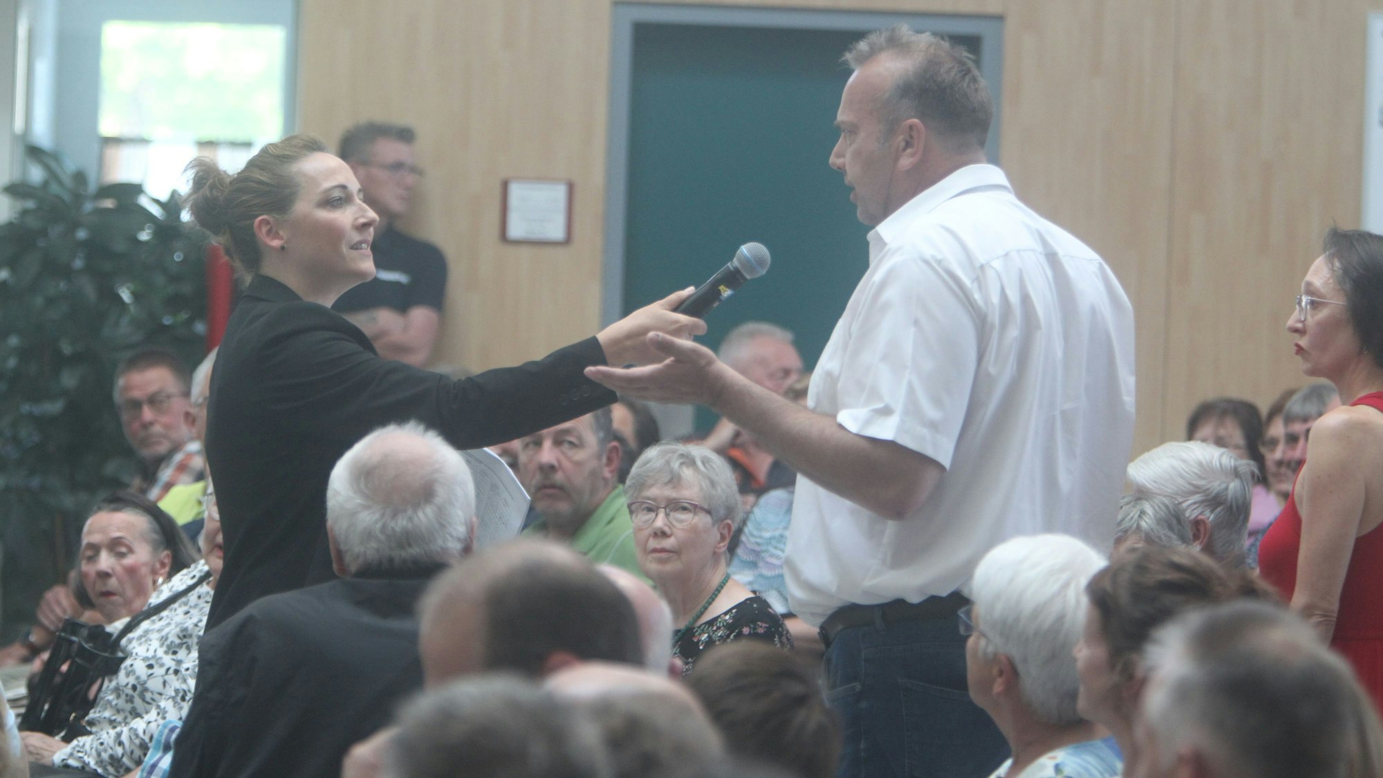In der Aula der Gesamtschule überreicht der Sprecher einer Bürgerinitiative Unterschriften an die Bürgermeisterin.