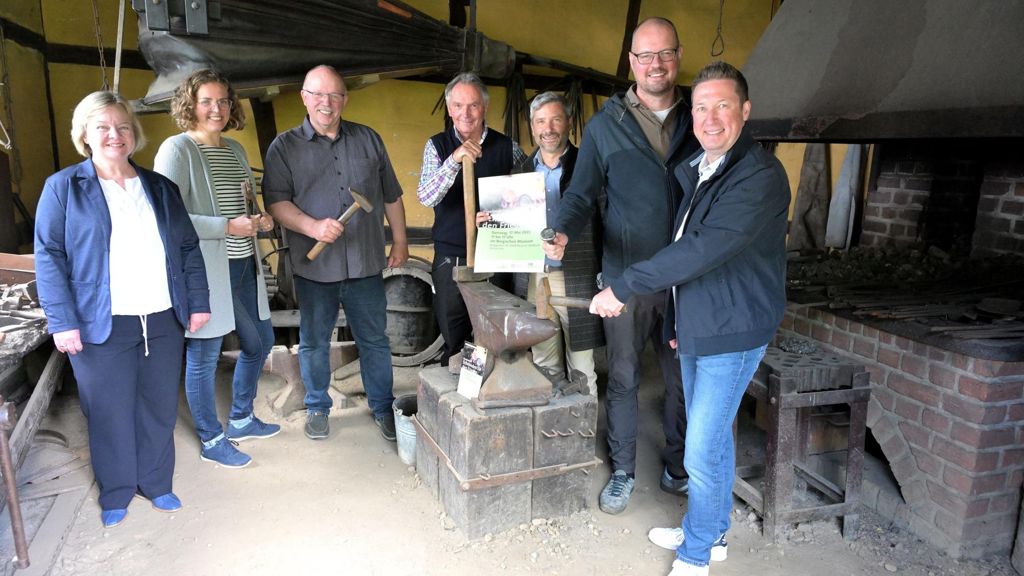 Menschen stehen um einen Amboss in der Schmiede des Bergischen Museums in Bergisch Gladbch-Bensberg.