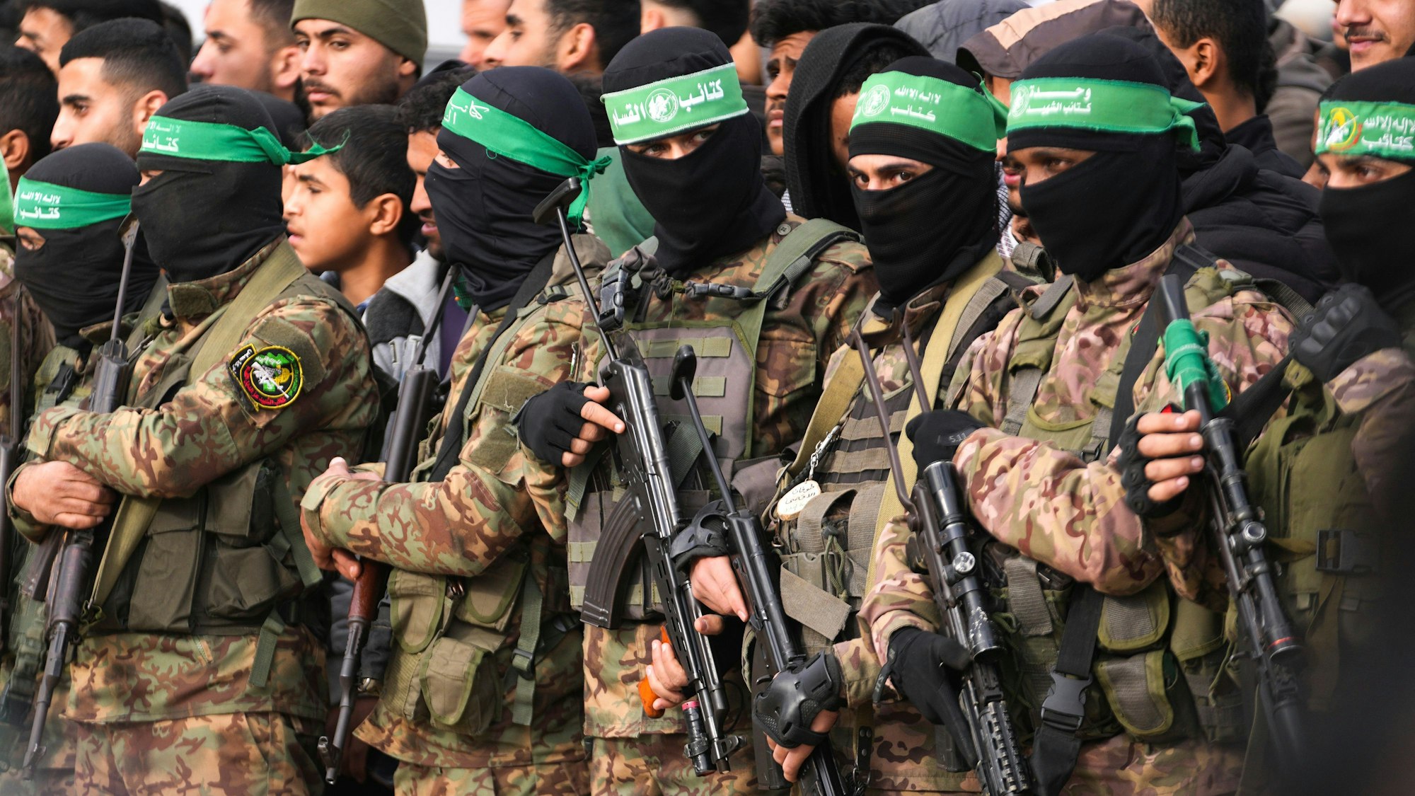 amas-Kämpfer stehen in Formation vor der Freilassung von Geiseln im zentralen Gazastreifen.