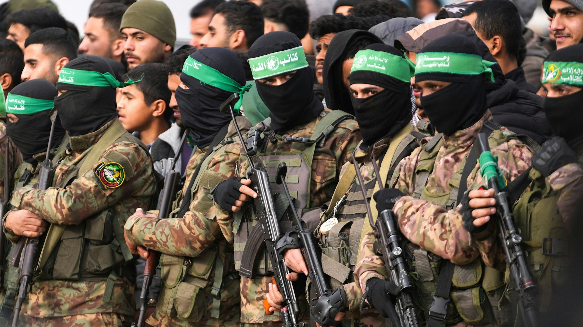Hamas-Kämpfer stehen in Formation vor der Freilassung von Geiseln im zentralen Gazastreifen.