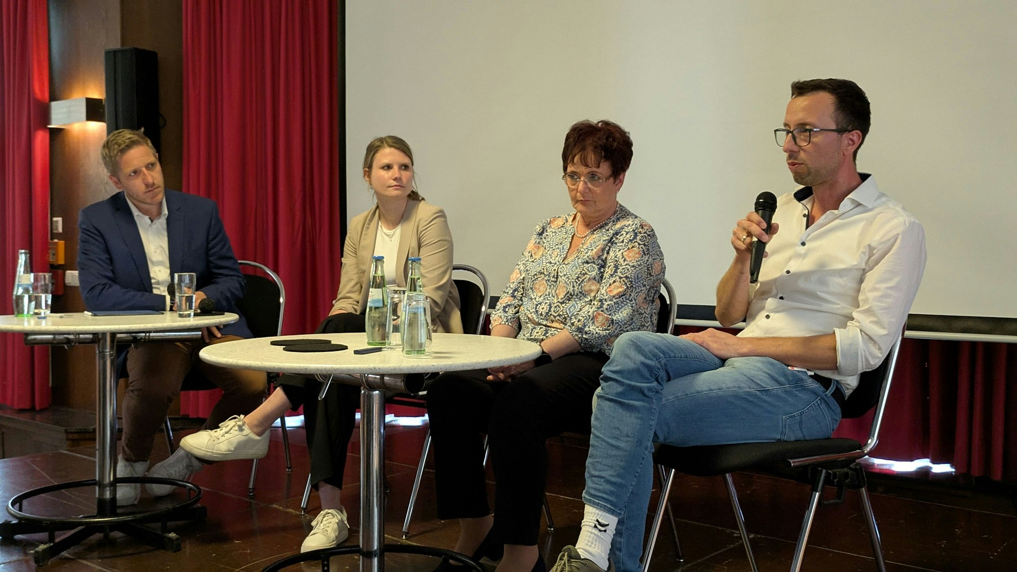 Markus Ramers, Jenny Wielga, Angela Steinhauer und Dr. Daniel Vermöhlen sitzen an einem Tisch, Vermöhlen hält ein Mikrofon in der Hand.