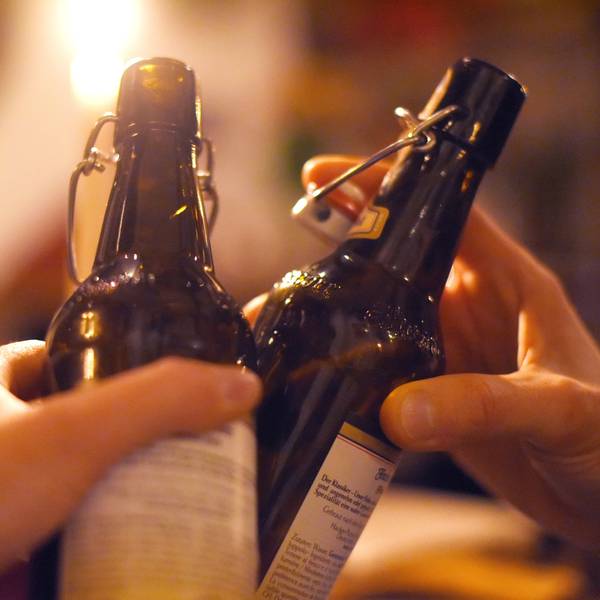 Zwei Händen mit Bierflaschen beim Anstoßen.