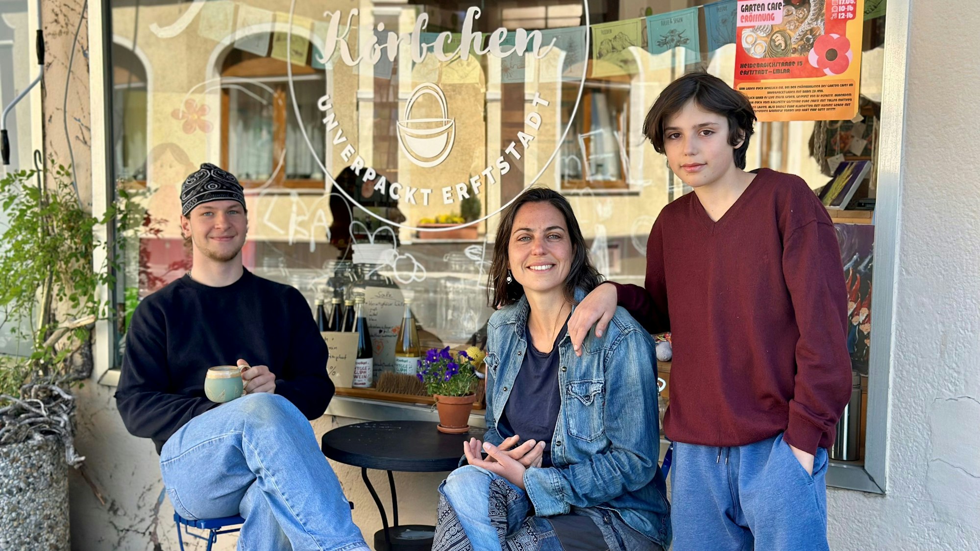 Ein Mann und eine Frau sitzen an einem Tisch, daneben steht ein Junge.