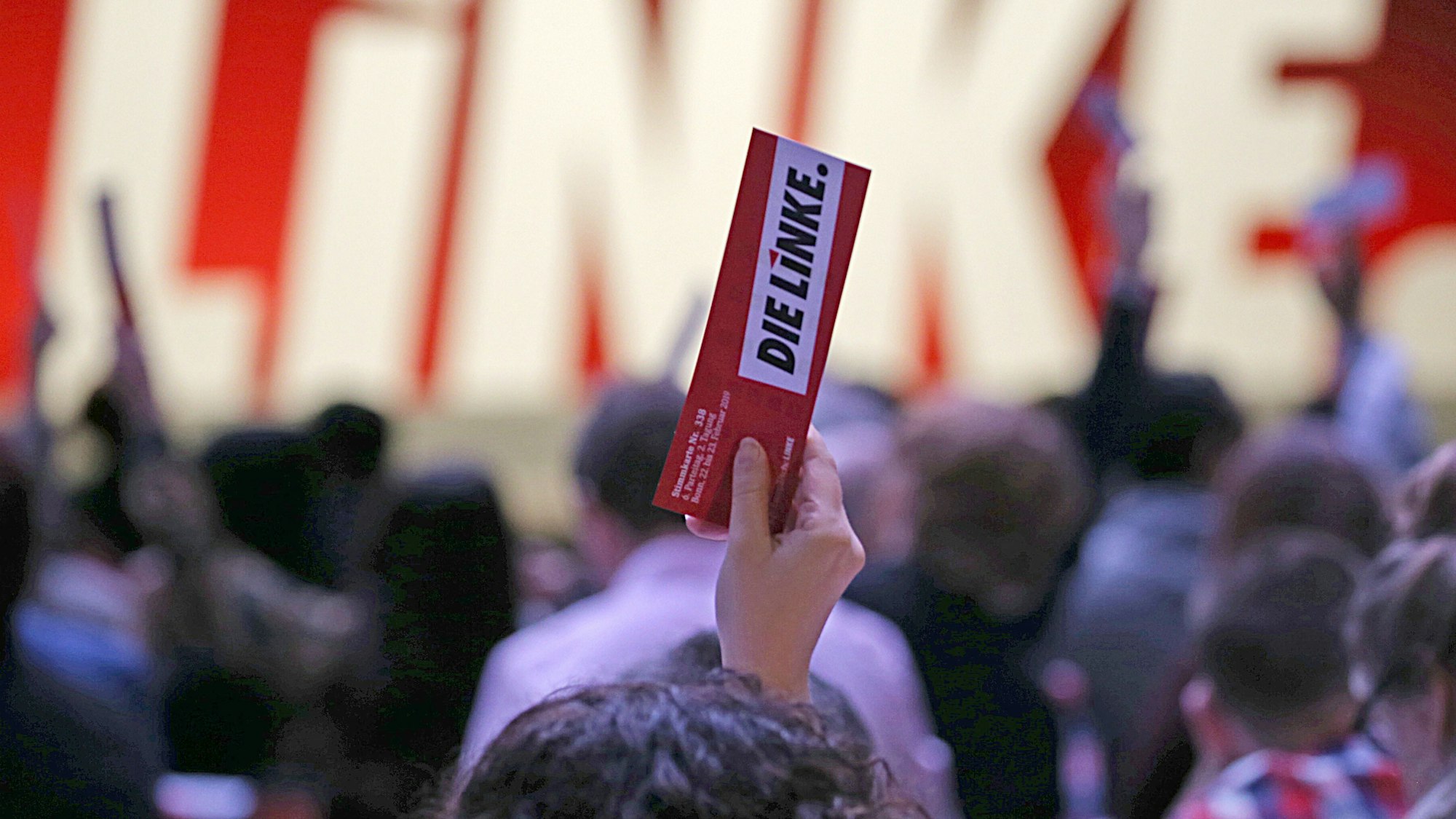 Eine Hand hält einen Flyer der Linken in die Höhe.