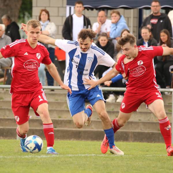 Das Bild zeigt einen Fußballer, dem zwei Gegner den Ball abnehmen wollen.