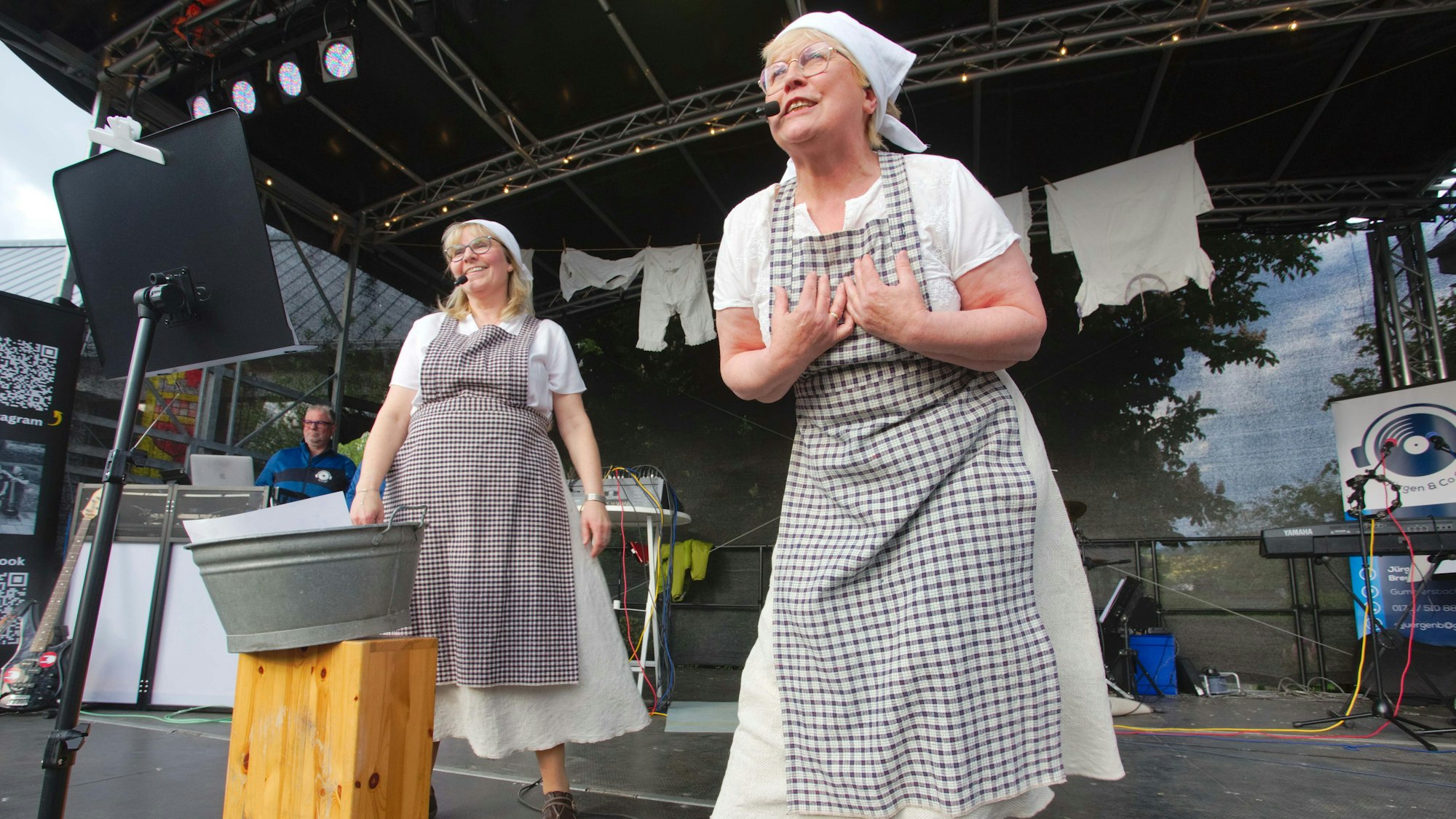 Zwei Frauen auf der Bühne in Kittelschürzen.