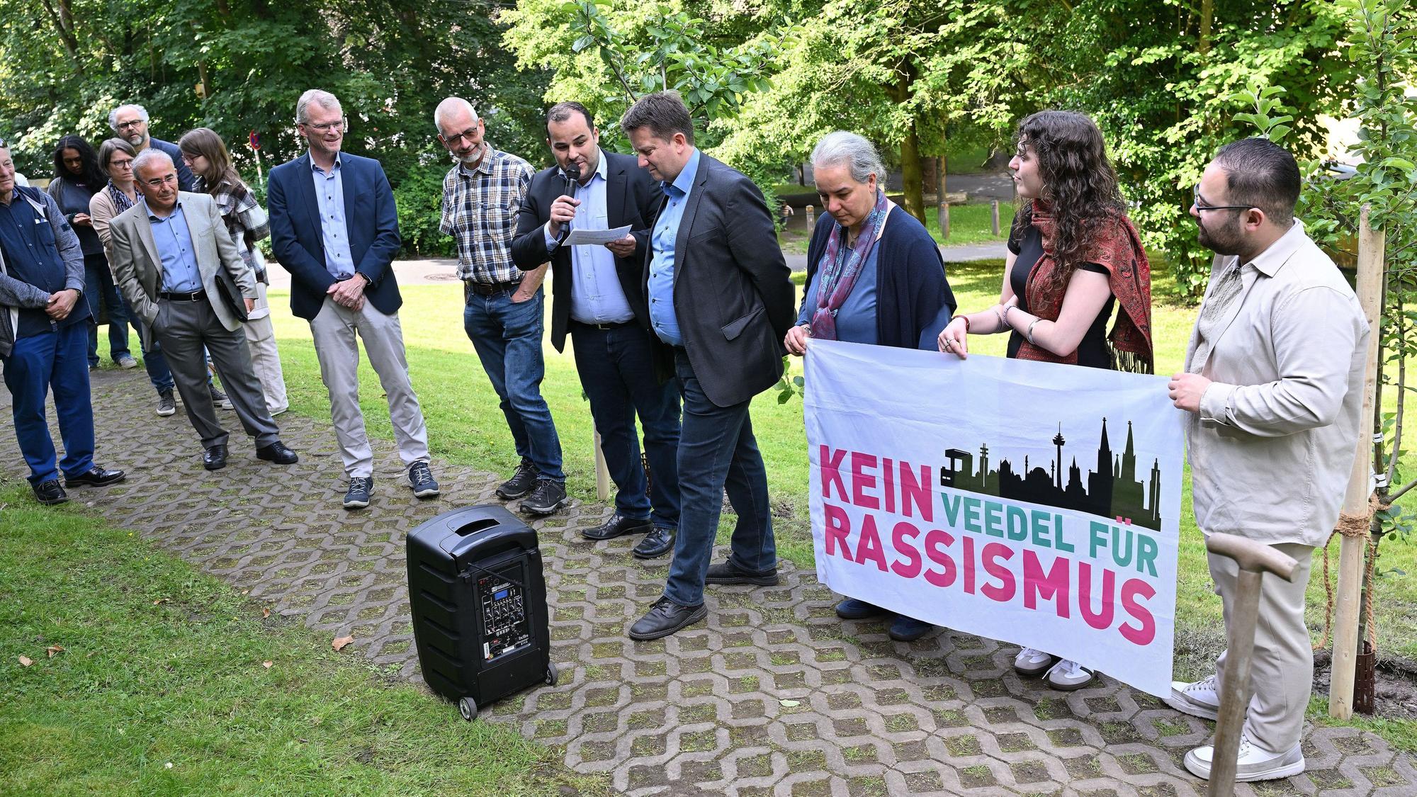 Beteiligte der Veranstaltung halten ein Anti-Rassismus-Plakat in der Hand.