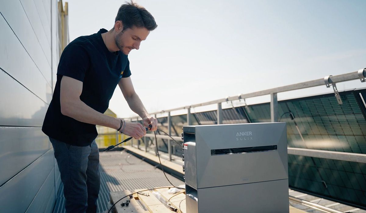Ein Solago Mitarbeiter installiert eine Anker Solix Solar-Speicherbank an Balkonkraftwerk Solarpanelen.