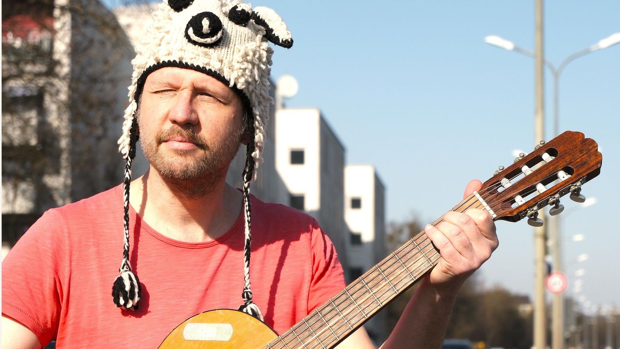 Thomas Franz mit Gitarre in der Hand und einer witzigen Wollmütze auf dem Kopf.