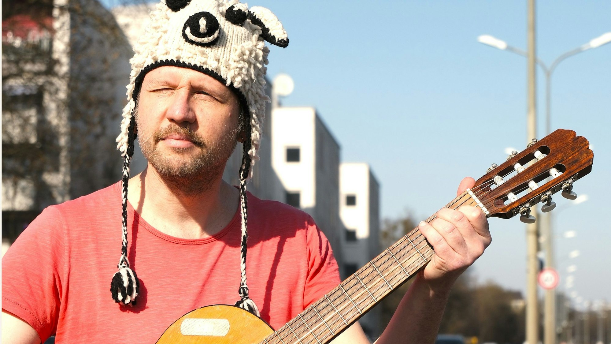 Thomas Franz mit Gitarre in der Hand und einer witzigen Wollmütze auf dem Kopf.