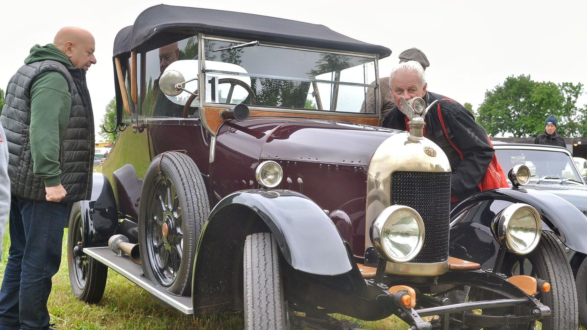 Zwei Besucher nehmen einen Oldtimer unter die Lupe.