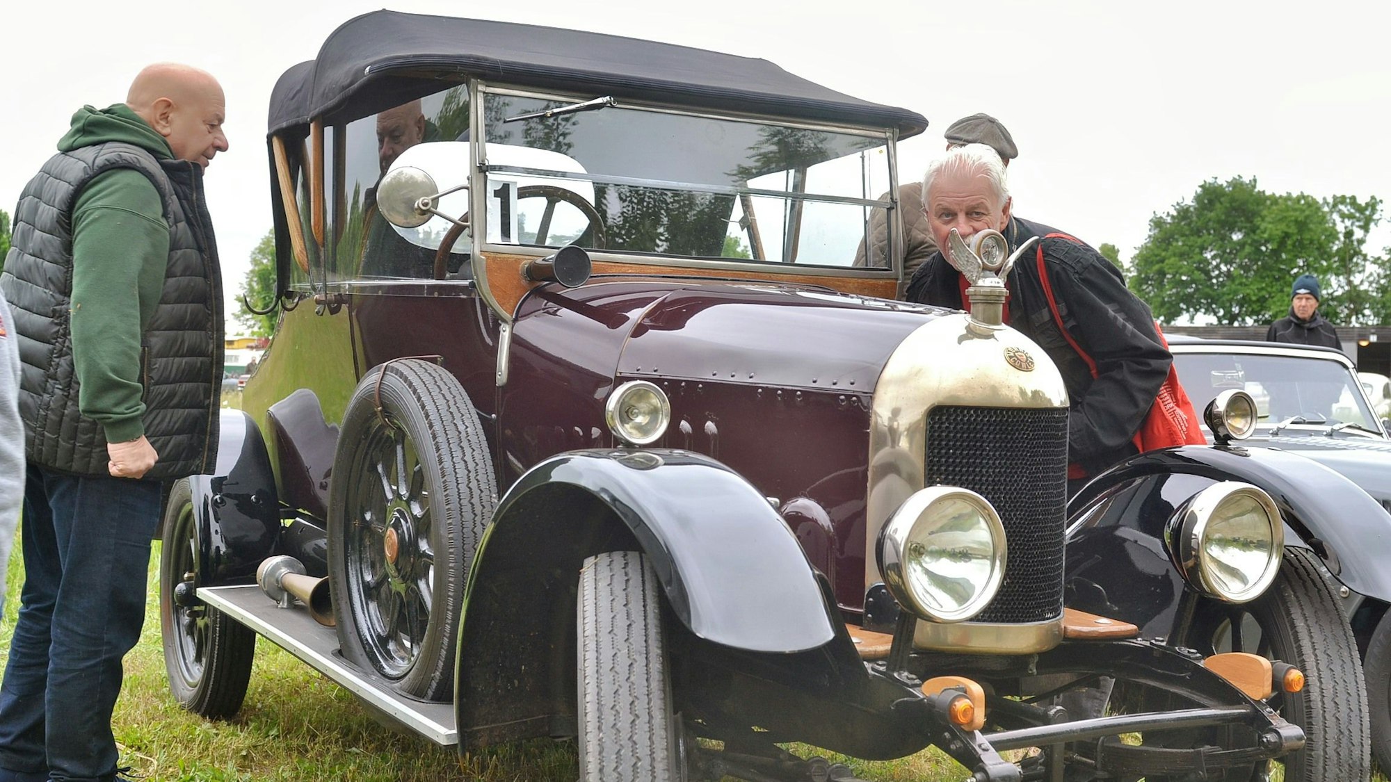 Zwei Besucher nehmen einen Oldtimer unter die Lupe.