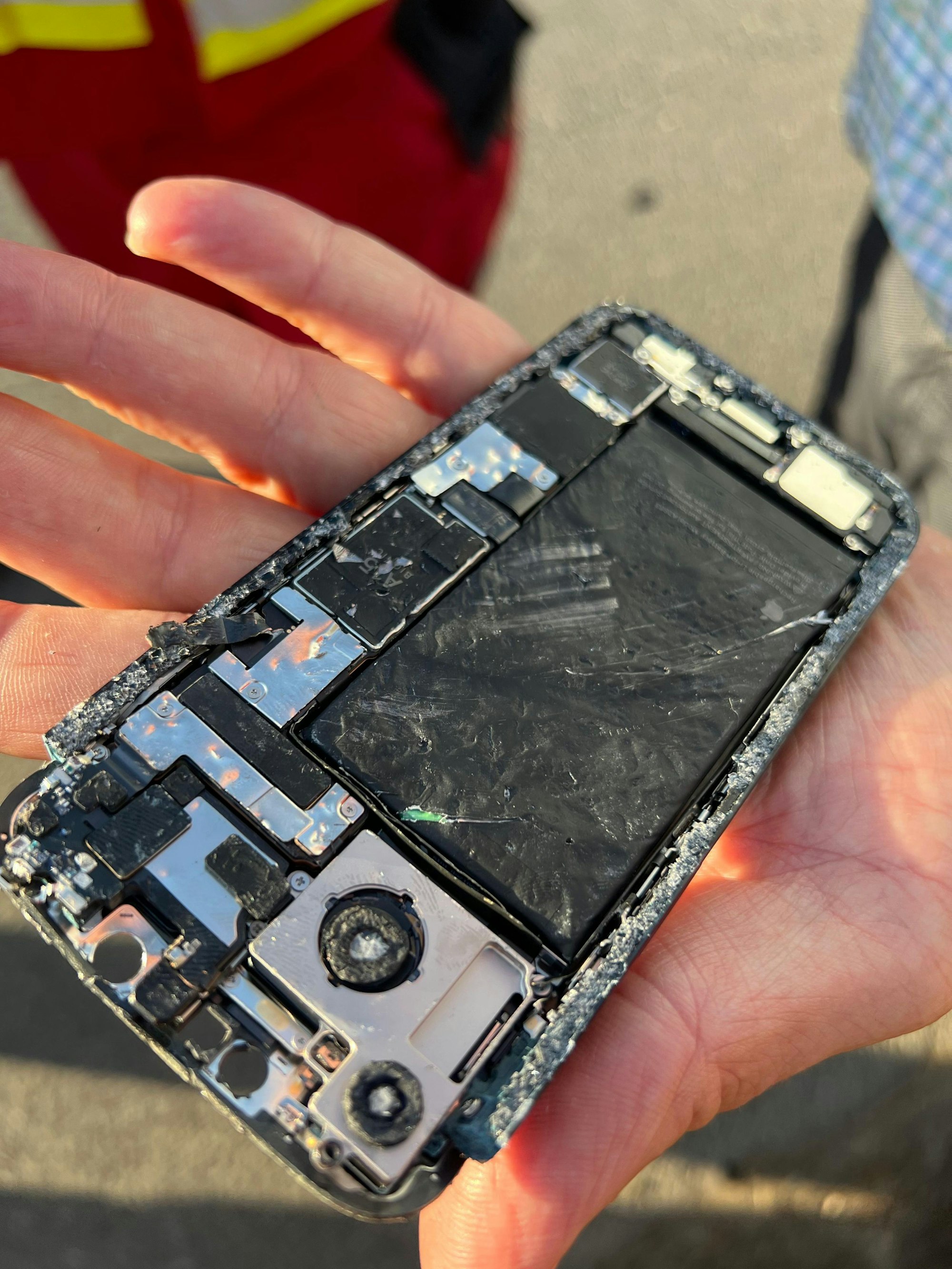 Eine Hand hält ein total zerstörtes Smartphone in den Händen.