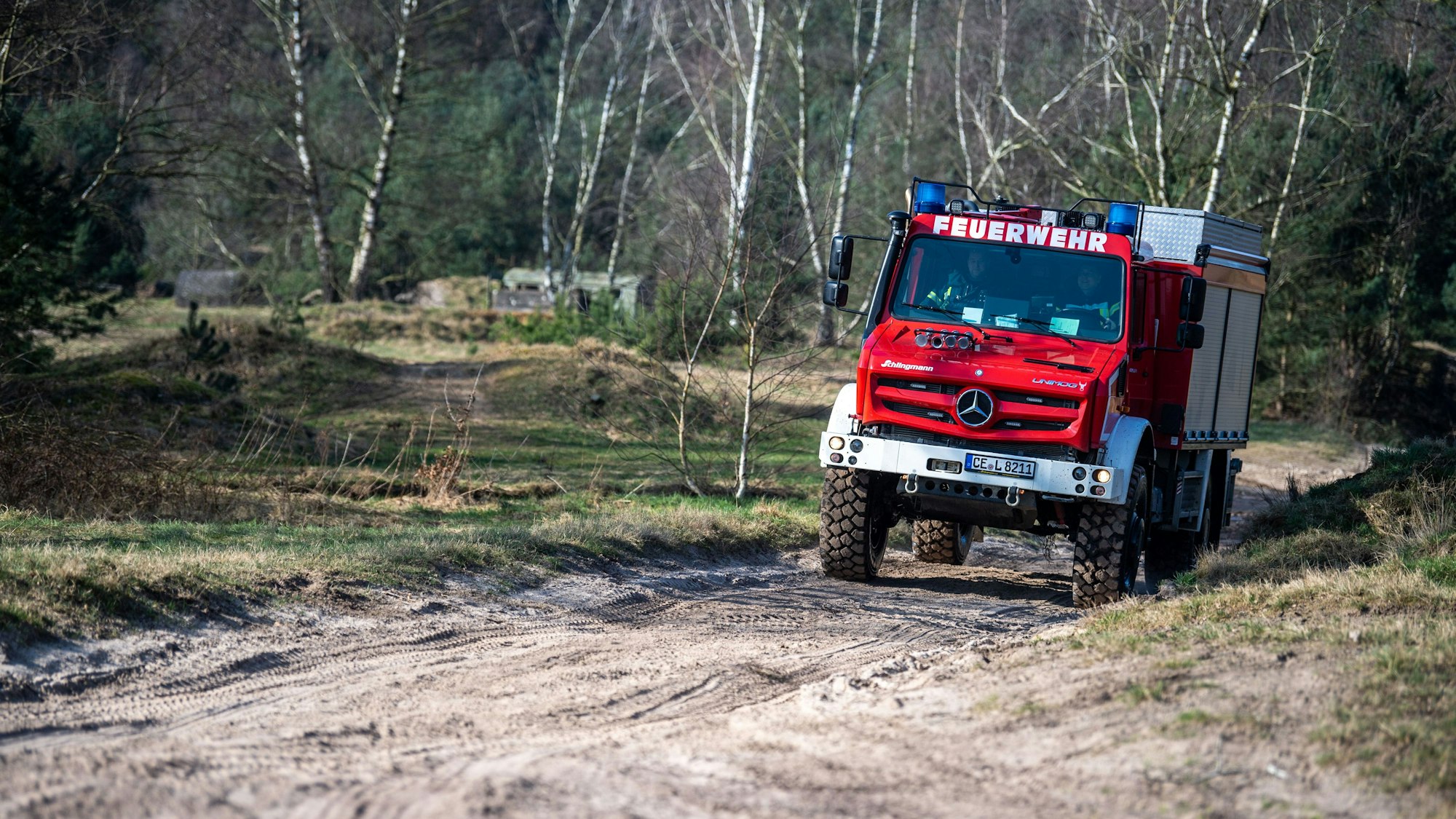 Ein TLF-W 3000 „Tanklöschfahrzeug-Waldbrand mit 3000l Wasser-Fassungsvermögen“ wird von Feuerwehrleuten über einen Militär-Übungsplatz gefahren.