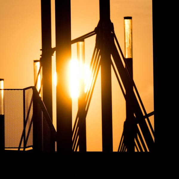09.04.2019, Niedersachsen, Hannover: Ein Mann geht mit einer Aktentasche bei Sonnenaufgang über eine Brücke an der Expo Plaza.