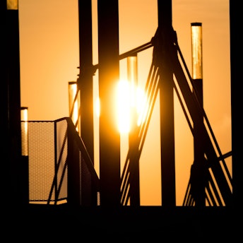 09.04.2019, Niedersachsen, Hannover: Ein Mann geht mit einer Aktentasche bei Sonnenaufgang über eine Brücke an der Expo Plaza.