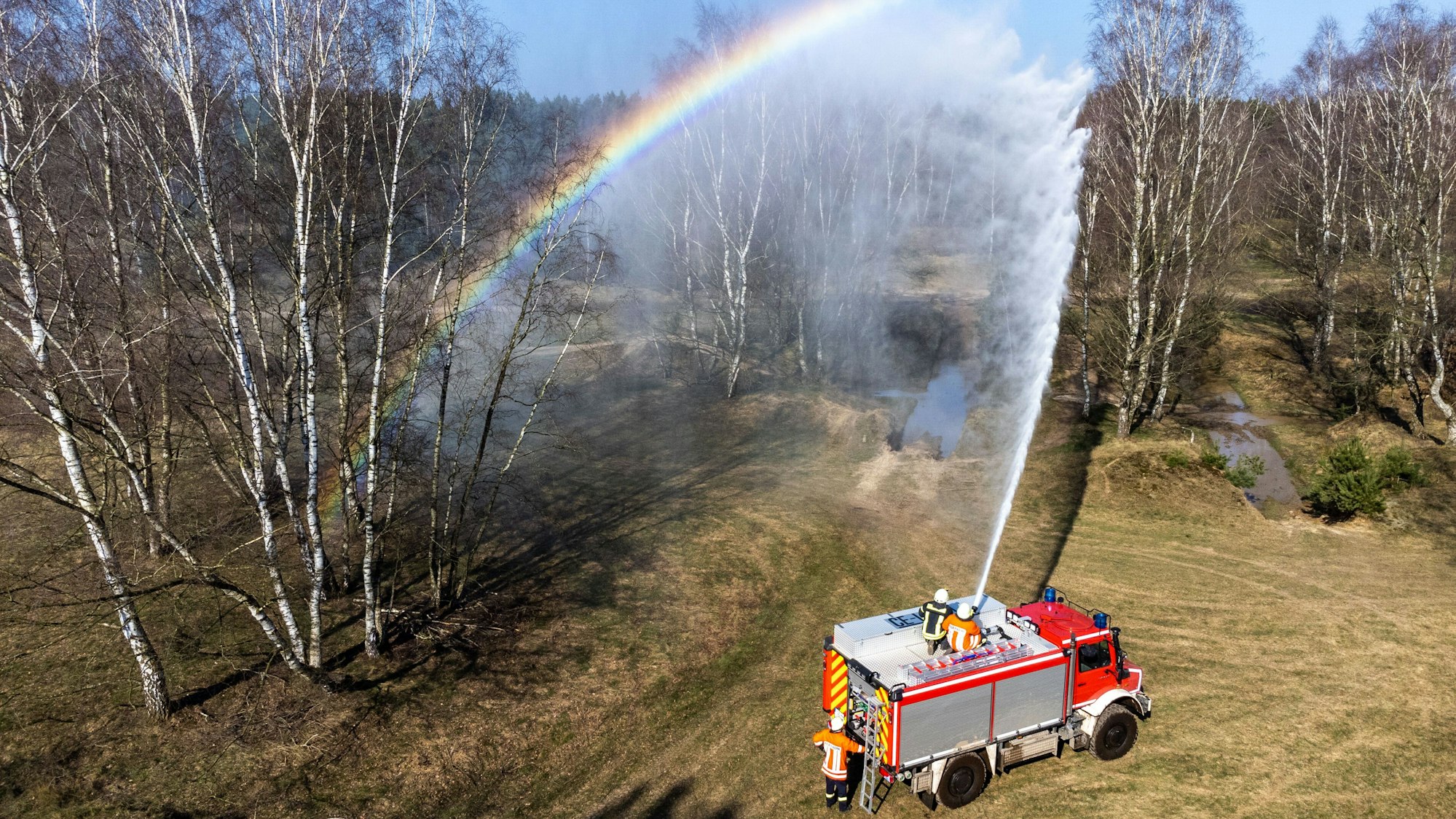 Ein TLF-W 3000 „Tanklöschfahrzeug-Waldbrand mit 3000l Wasser-Fassungsvermögen“ Sprüht über einen sogenannten Dachmonitor mit 2000 Litern die Minute Wasser auf ein Militär-Übungsgelände und erzeugt dabei einen Regenbogen.