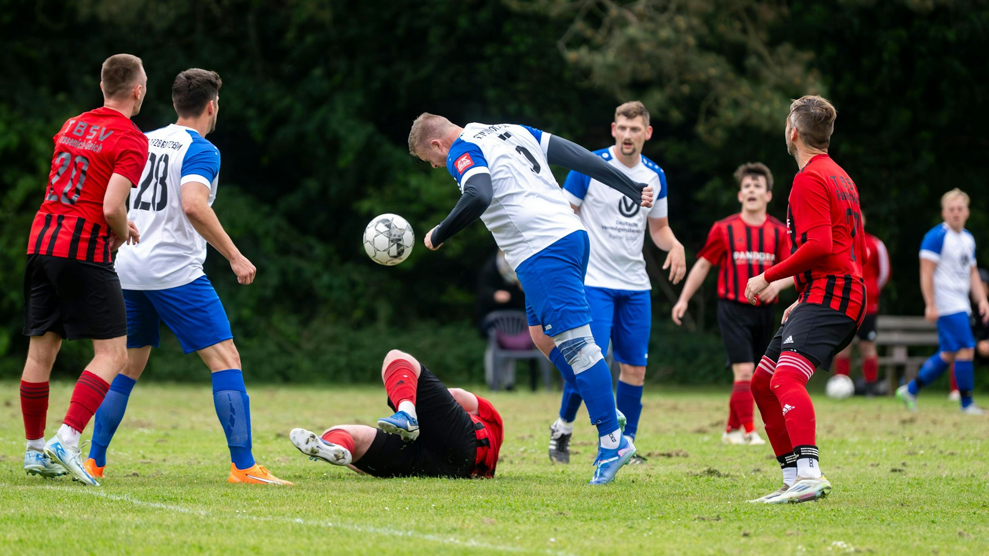 Ein Fußballer steht unorthodox zum Ball. Vor ihm liegt ein Gegenspieler, den er zuvor gefoult hatte.