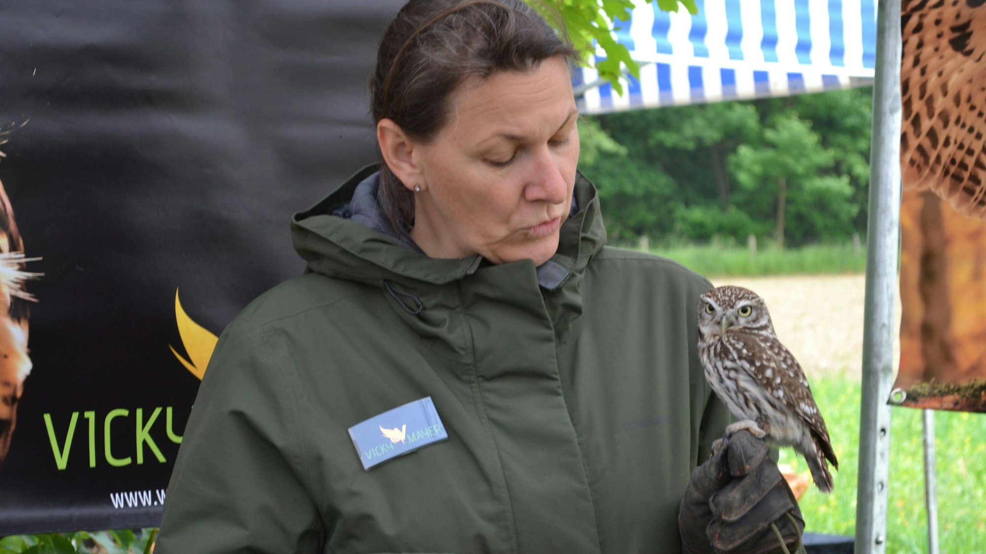 Eine Frau hält einen Steinkauz auf ihrer Hand.