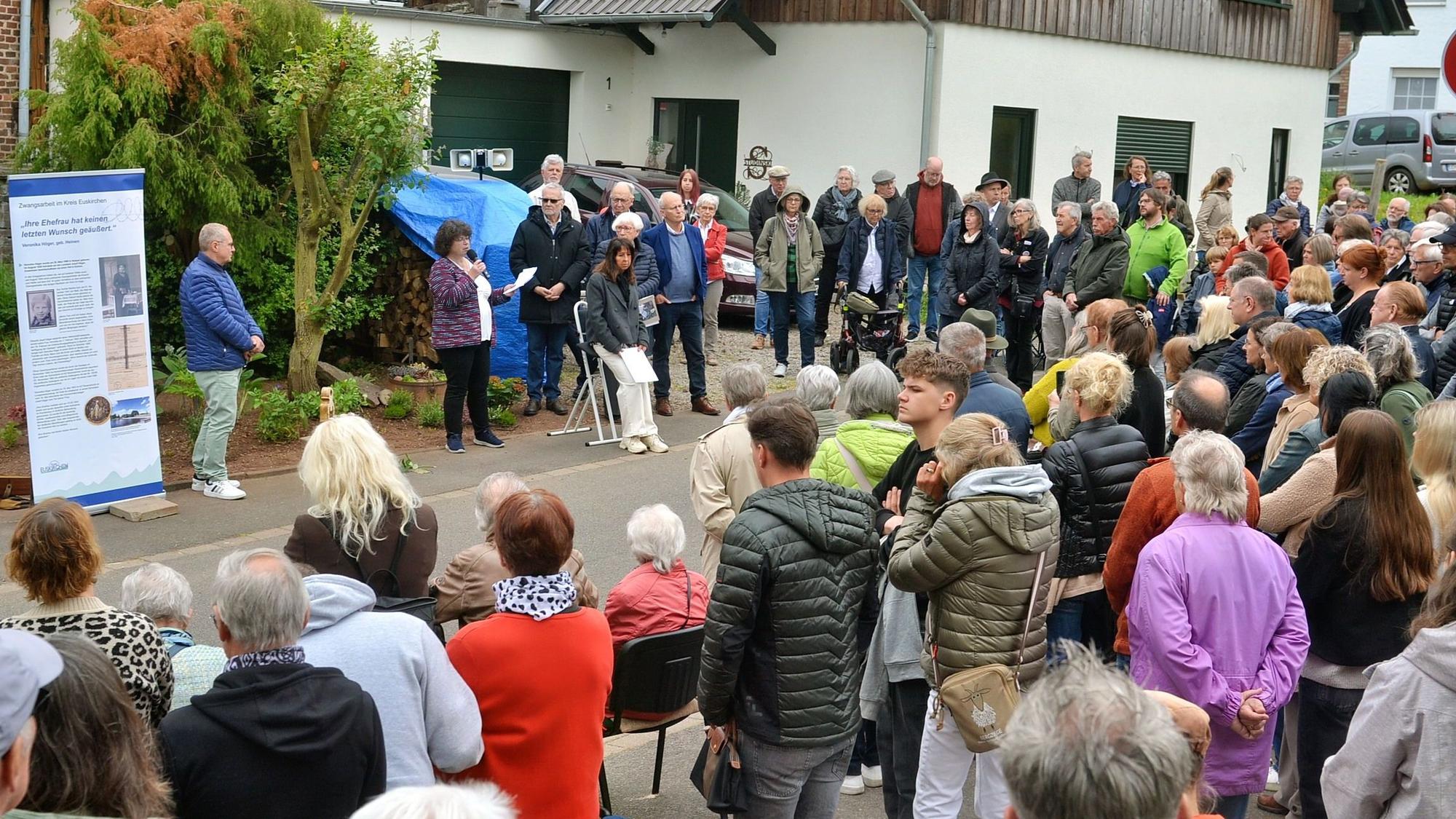 Die Besucher stehen um eine Gedenktafel und hören dem Vortrag von Heike Pütz zu.