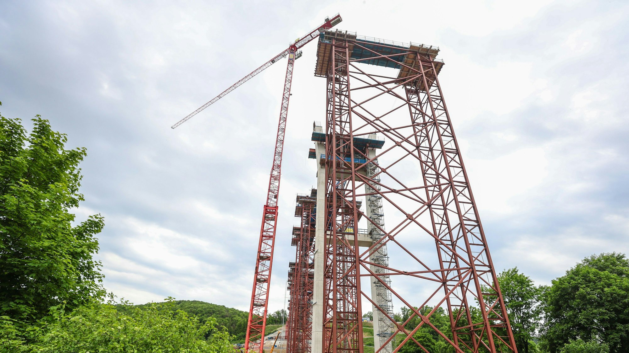 Ein Kran steht auf einer Brückenbaustelle neben einem Gerüst.