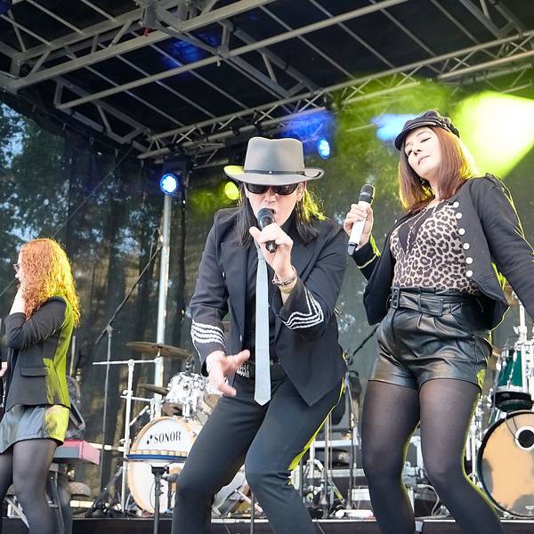 Ein Mann als Udo Lindenberg verkleidet singt in ein Mikrofon, daneben tanzt eine Frau.