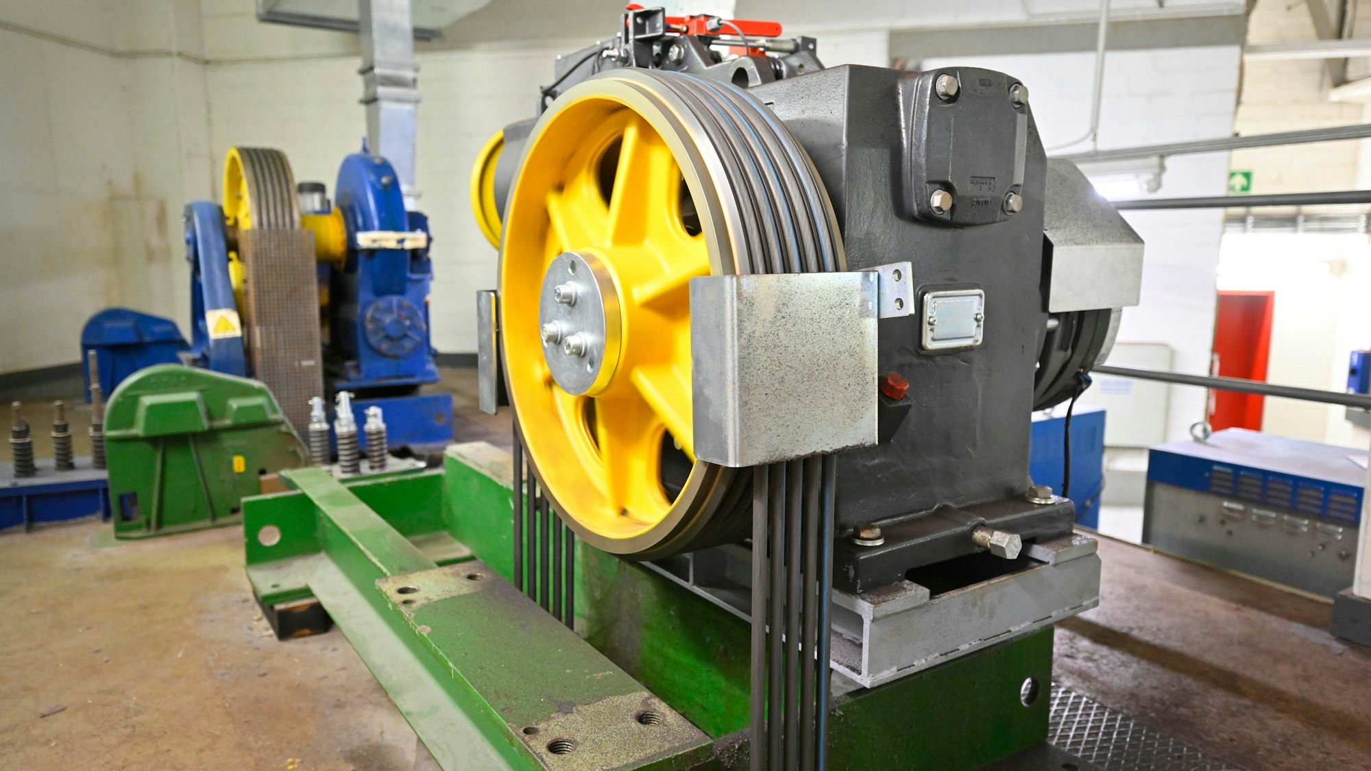 Große gelbe Scheibe, die zu einem Motor gehört, der einen der zehn Aufzüge antreibt.