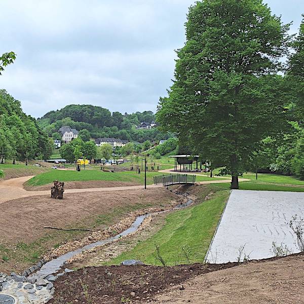 Das Bild zeigt die neue Parkanlage in Blankenheim mit Sandwegen und einem Bach.