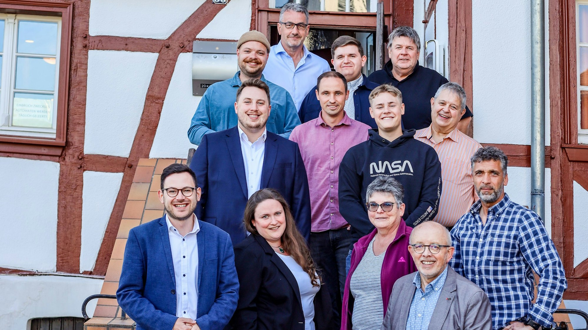 Die SPD-Kandidaten stehen auf der Treppe zur Gaststätte Gier, die in einem Fachwerkhaus ist.