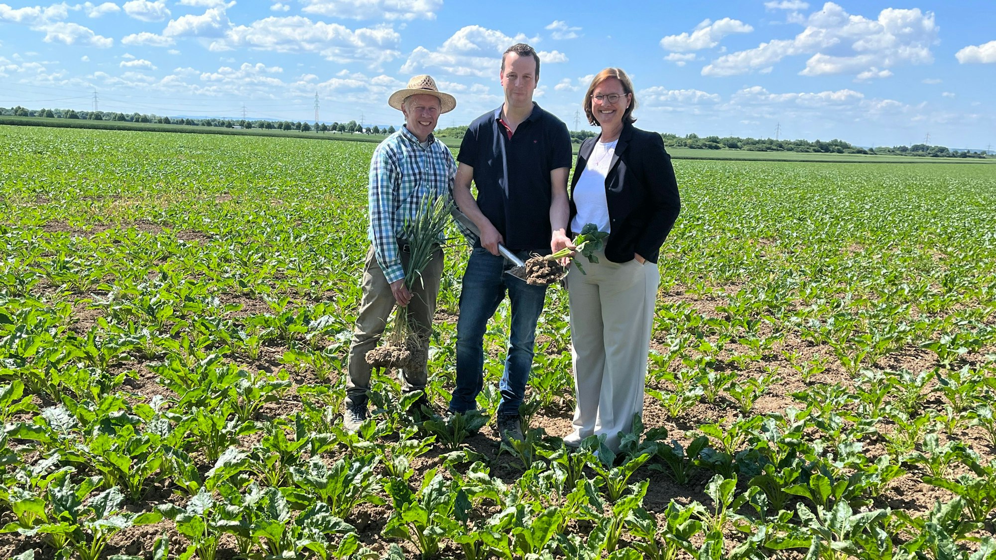 Zwei Männer und eine Frau stehen auf einem grüner Acker