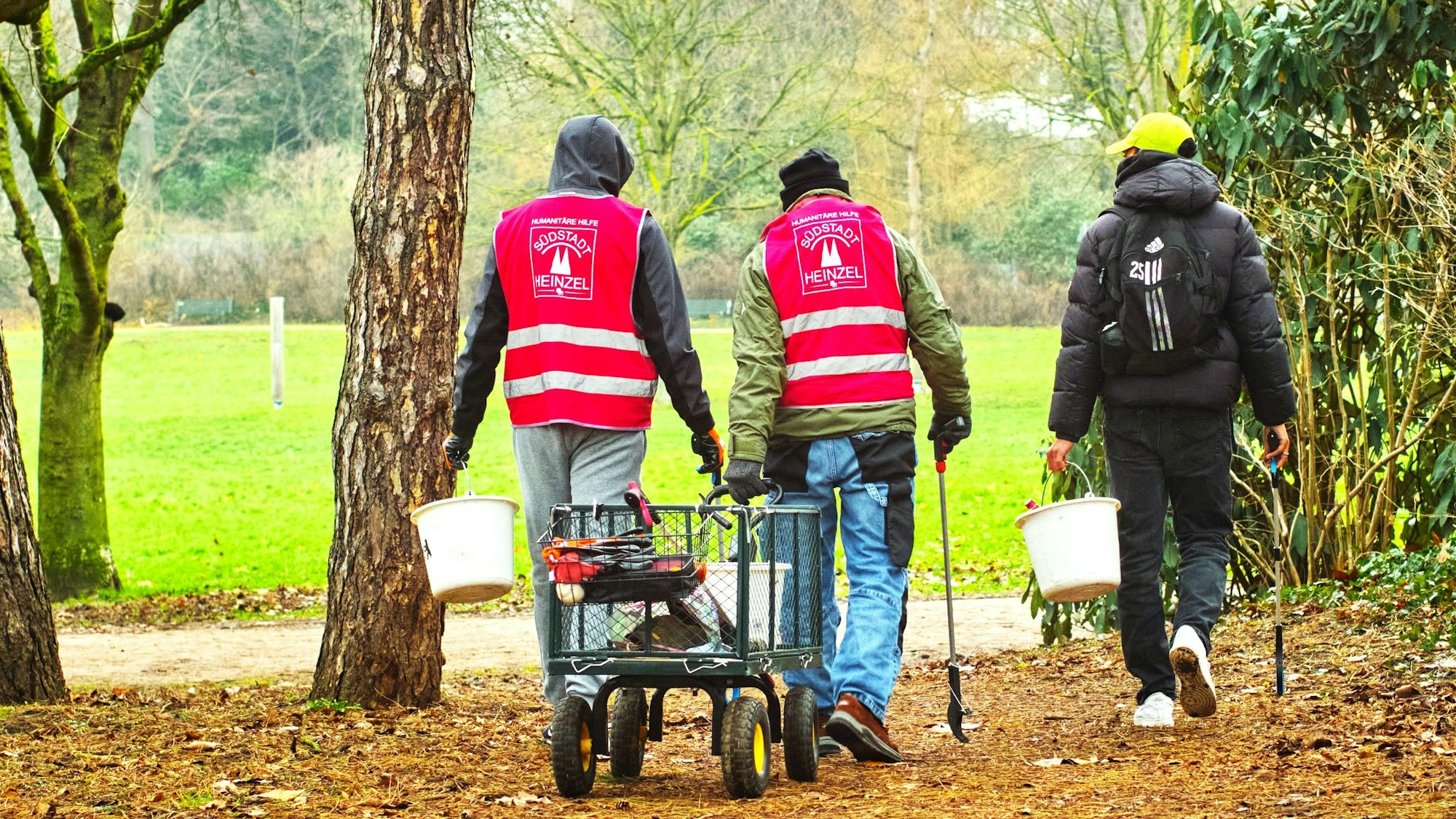 Drei Männer im Volksgarten sammeln Müll