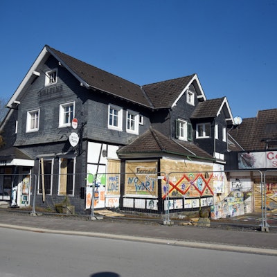Ein altes Haus mit verbretterten Fenstern und besprühter Fassade.