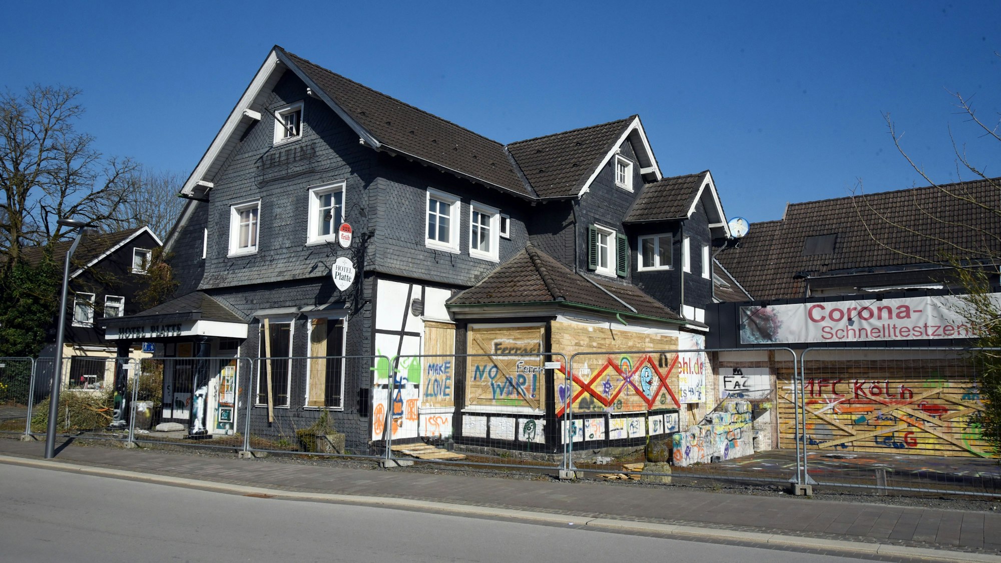Ein altes Haus mit verbretterten Fenstern und besprühter Fassade.