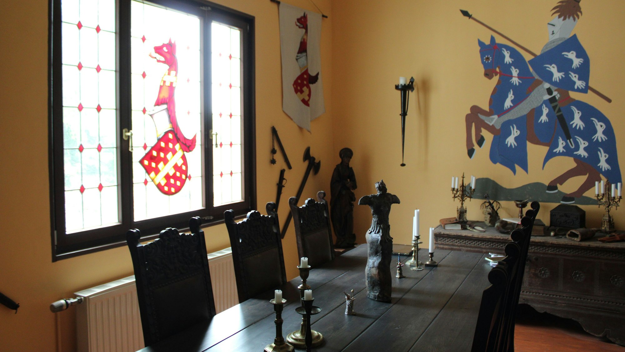 In das Bleiglasfenster in ihrem Esszimmer haben Melchior und Prahl das Wappen der Familie von Markelsbach einarbeiten lassen, den Ritter an der Wand haben sie selbst gemalt.