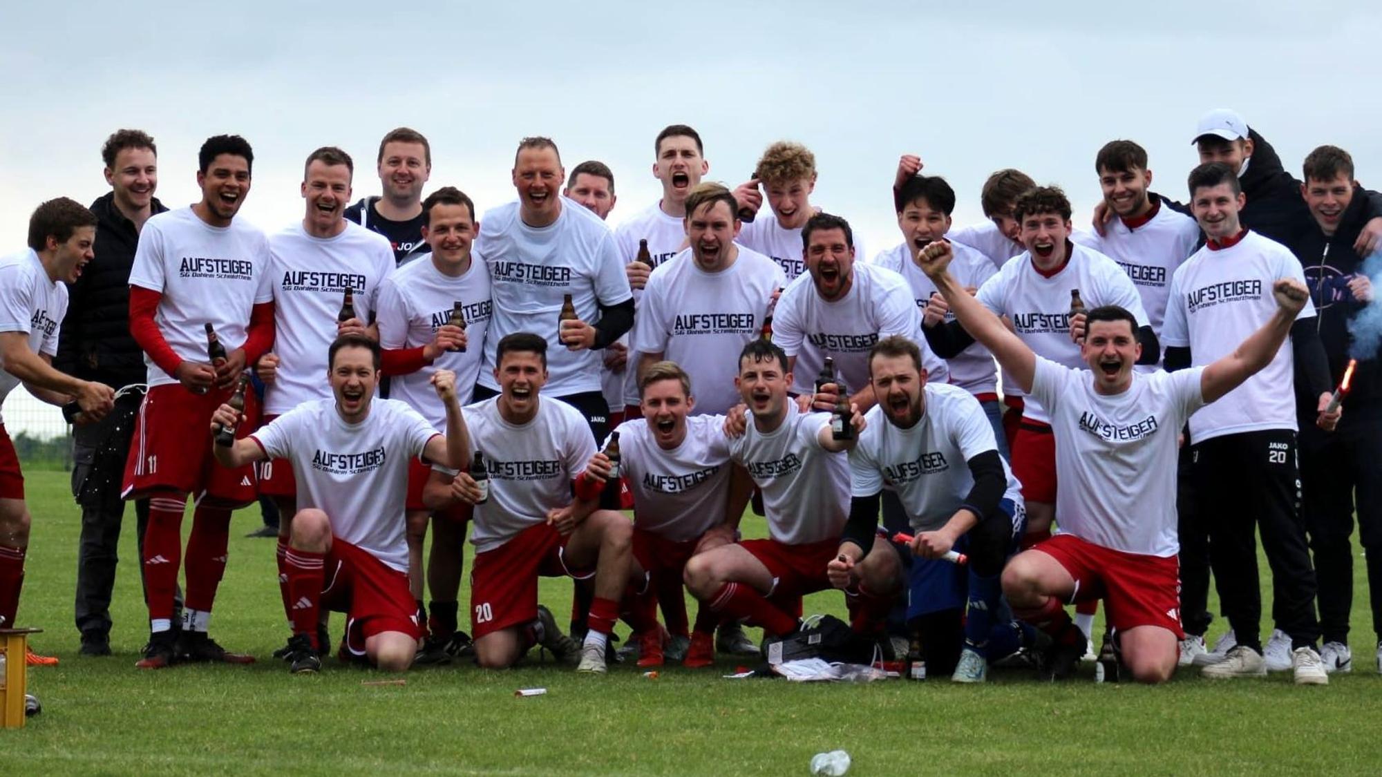 Das Foto zeigt eine Fußball-Mannschaft in weißen Trikots und roten Hosen, die für ein Foto posiert.