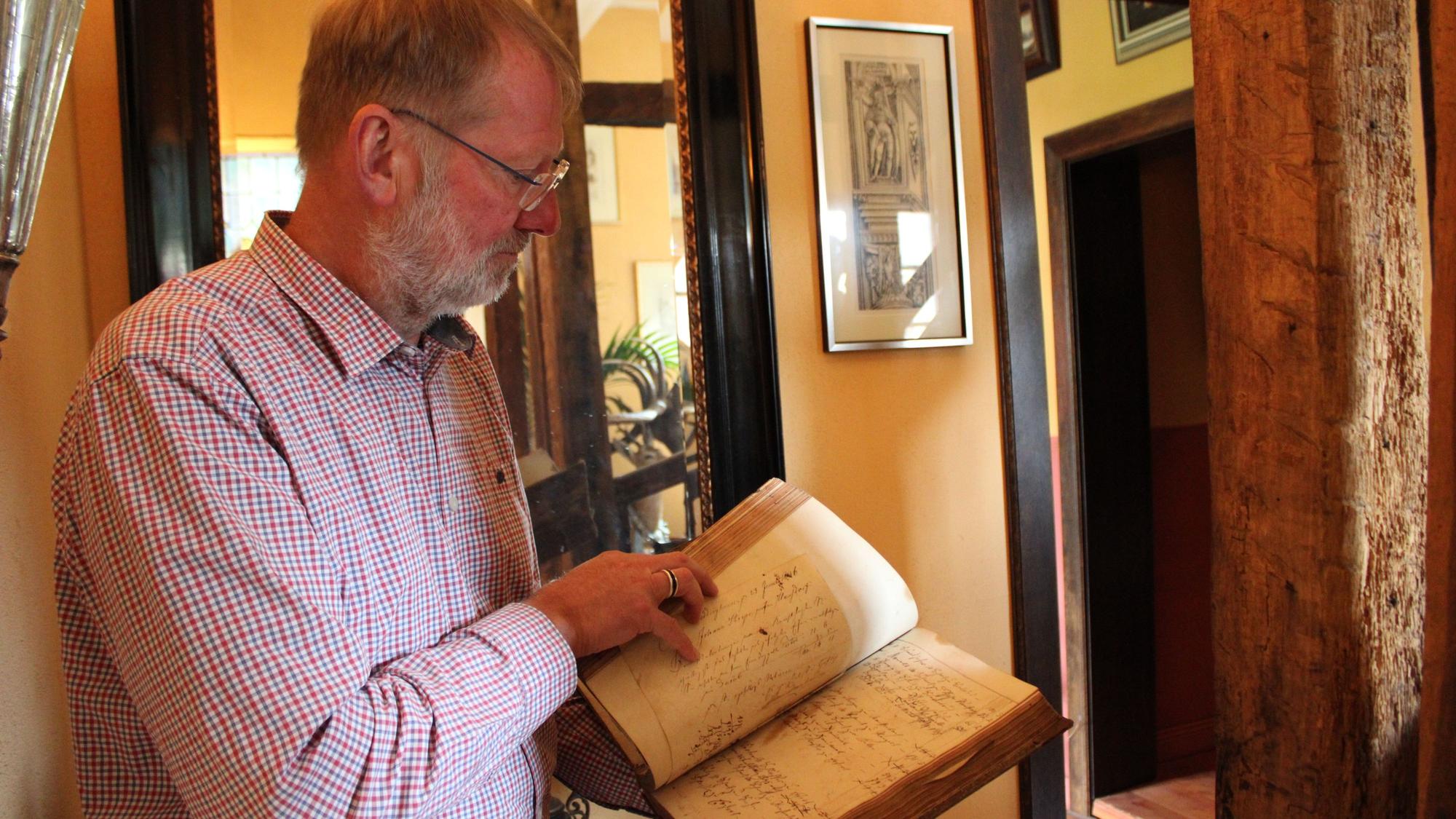 Gerd Melchior mit einem alten „Hammerbuch“ aus dem Haus Dorp, in dem hier noch zu Mittelalterzeiten Einnahmen und Ausgaben festgehalten wurden.